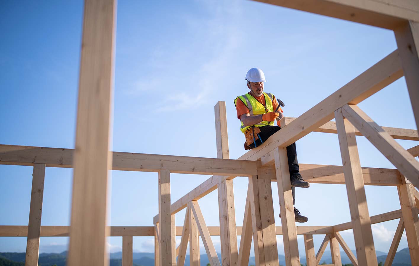 Mann auf Baustelle im Holzrohbau sitzend