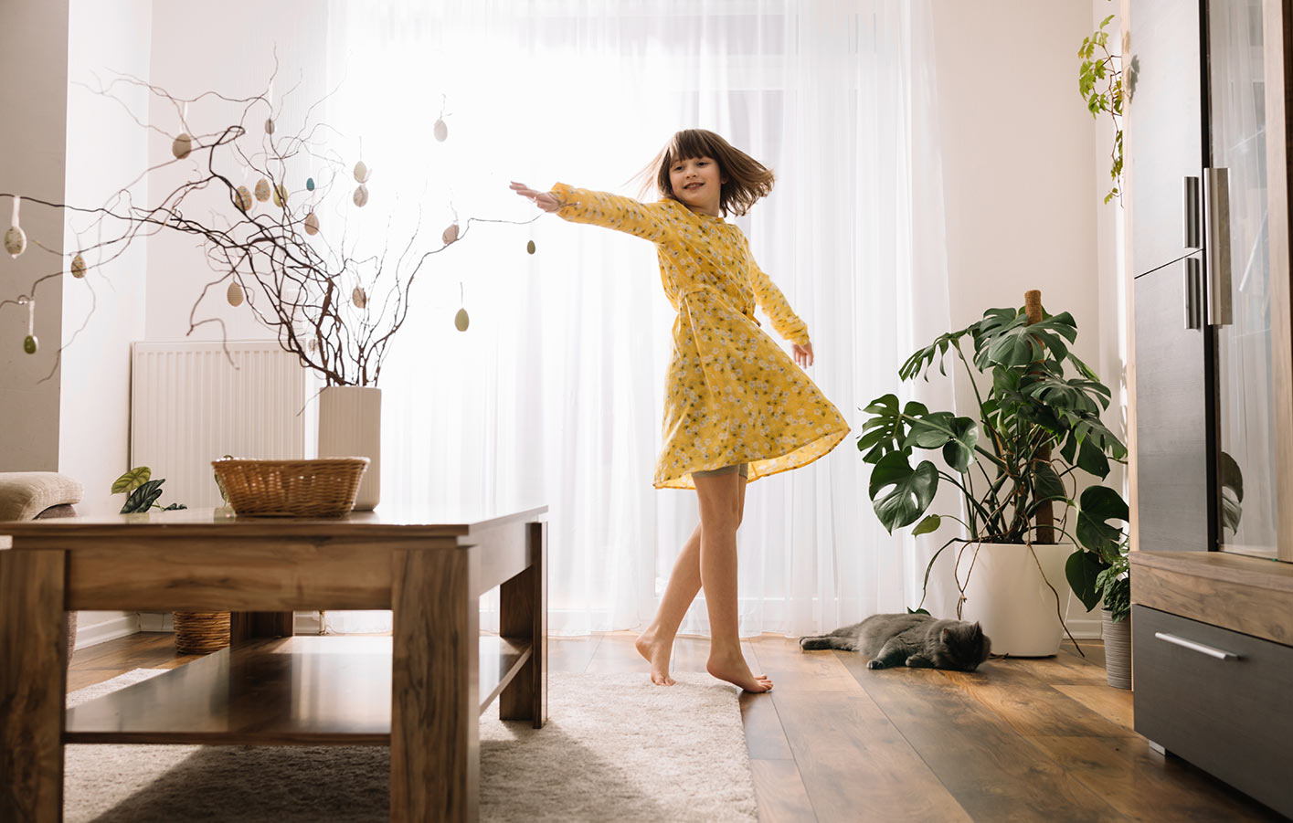 Kind tanzt im Wohnzimmer auf Parkettboden